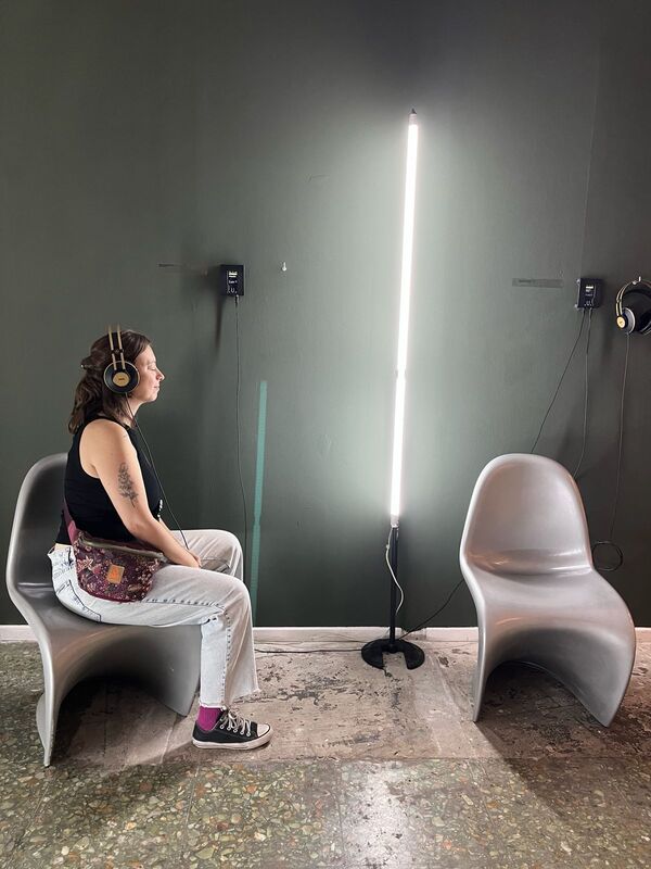 A profile view of a person seated listening to Beatriz Ferreyra